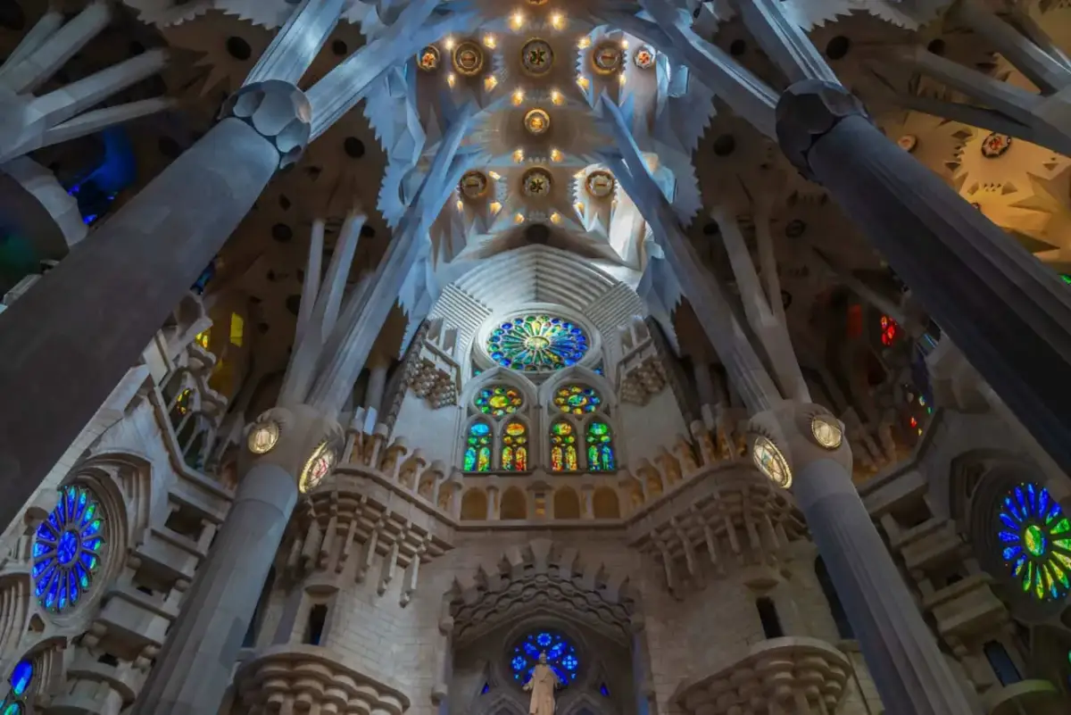 Wnętrze Sagrada Familia zachwyca kamiennymi kolumnami przypominającymi drzewa i kolorowymi witrażami.