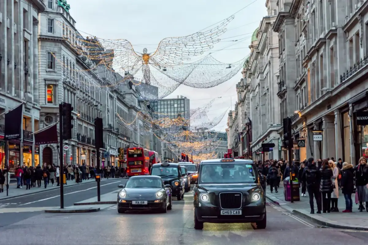 Świąteczne iluminacje nad ulicą w Londynie, z charakterystycznym czarnym taksówką i czerwonym autobusem. Piccadily Circus w całej okazałości.