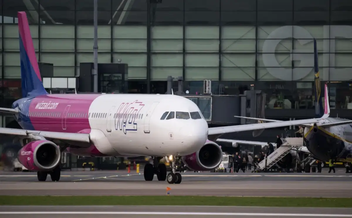 Samolot Wizz Air na płycie lotniska przed budynkiem terminala.