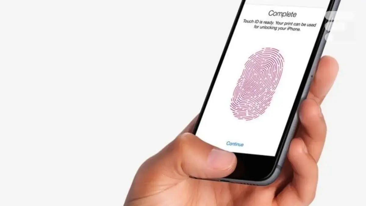 Main d'une personne tenant un iPhone 13, configurant le Touch ID pour déverrouiller son appareil.