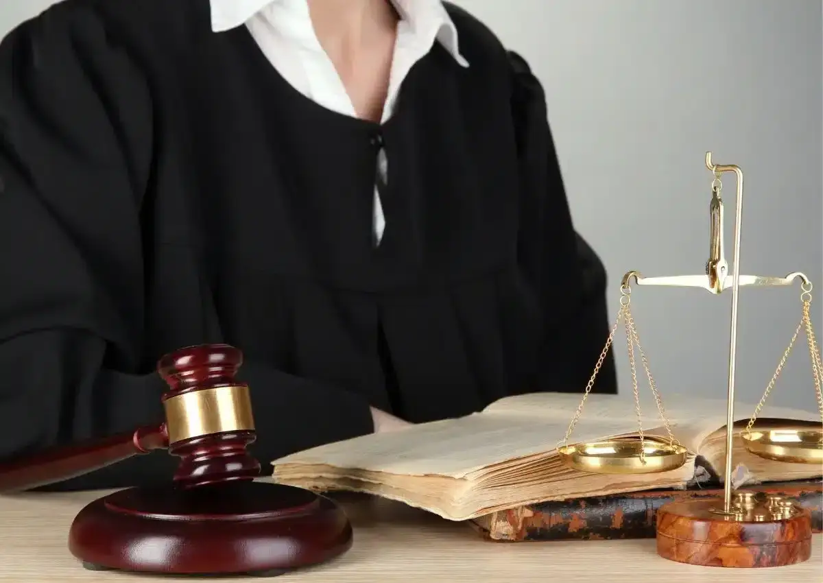 Sąd w todze, młotek sędziowski, waga sprawiedliwości i księgi prawne.