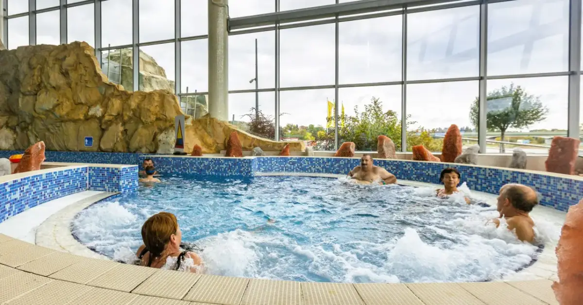 Ludzie relaksują się w jacuzzi. Szukając, które termy są najtańsze, warto sprawdzić oferty z podobnymi atrakcjami.