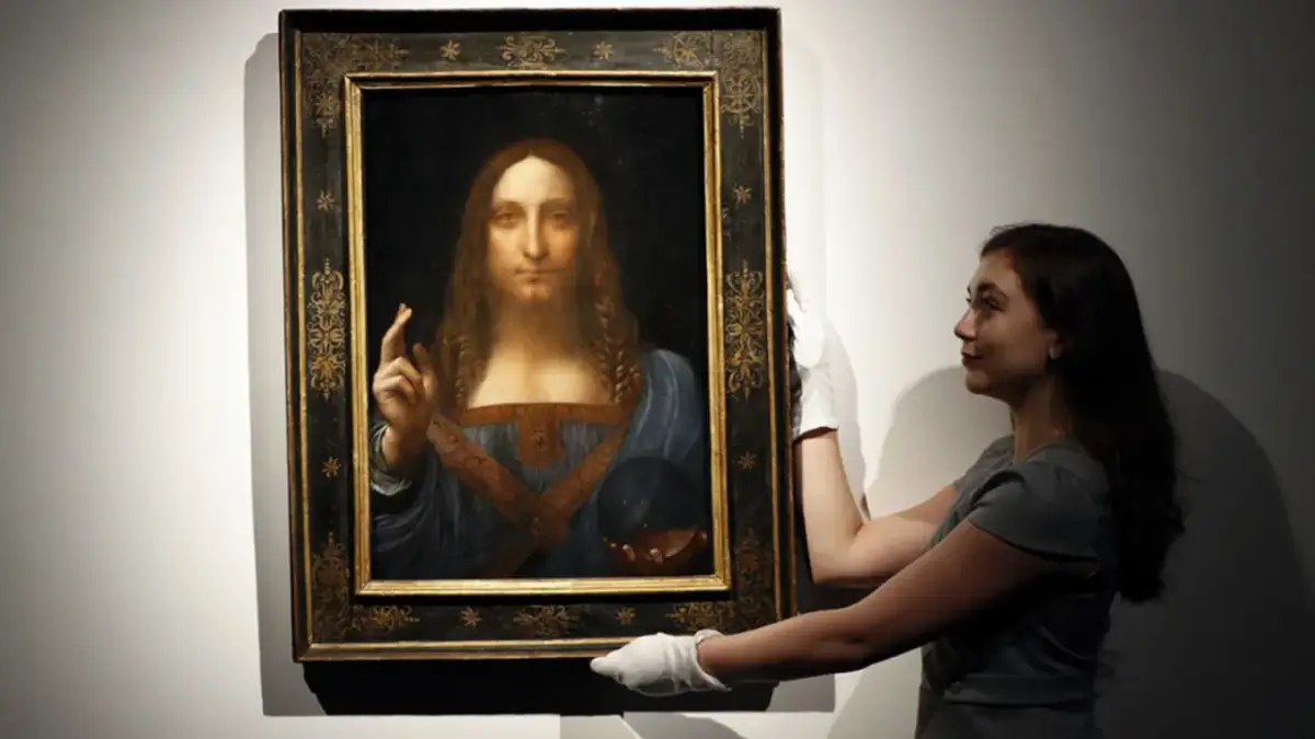 Frau mit weißen Handschuhen präsentiert das Gemälde "Salvator Mundi" von Leonardo da Vinci.