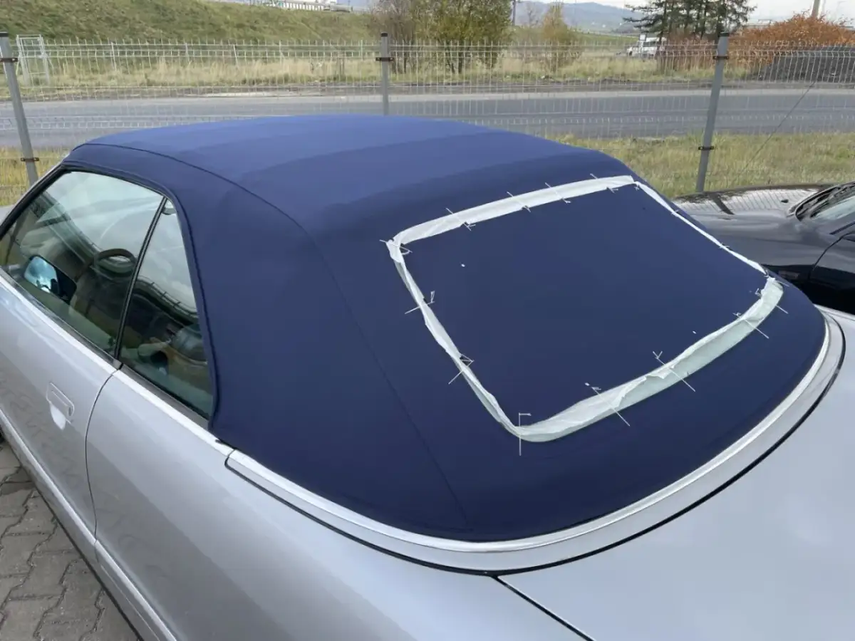 Granatowy dach cabrio w trakcie szycia, z widocznymi białymi nićmi mocującymi.