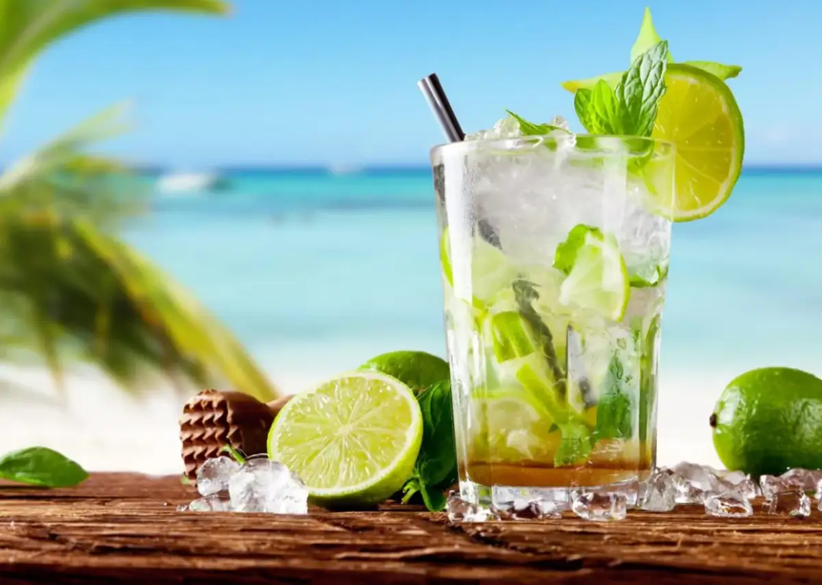 Orzeźwiający mojito na plaży, z limonkami i miętą, w tle błękitne morze i palmy. Idealny na upalny dzień.