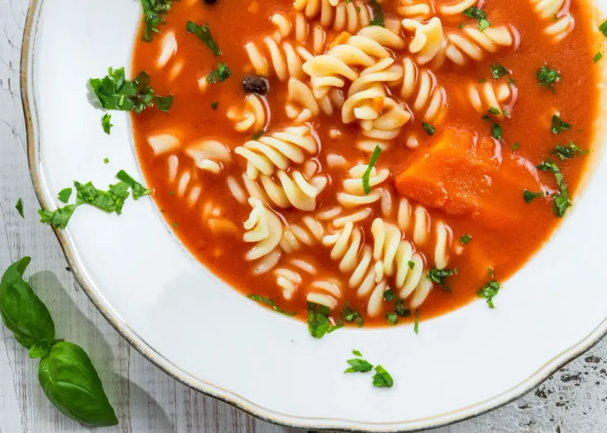 Zupa pomidorowa z makaronem fusilli i kawałkami marchewki. Aby jak zmniejszyć kwasowość zupy, dodaj szczyptę sody.