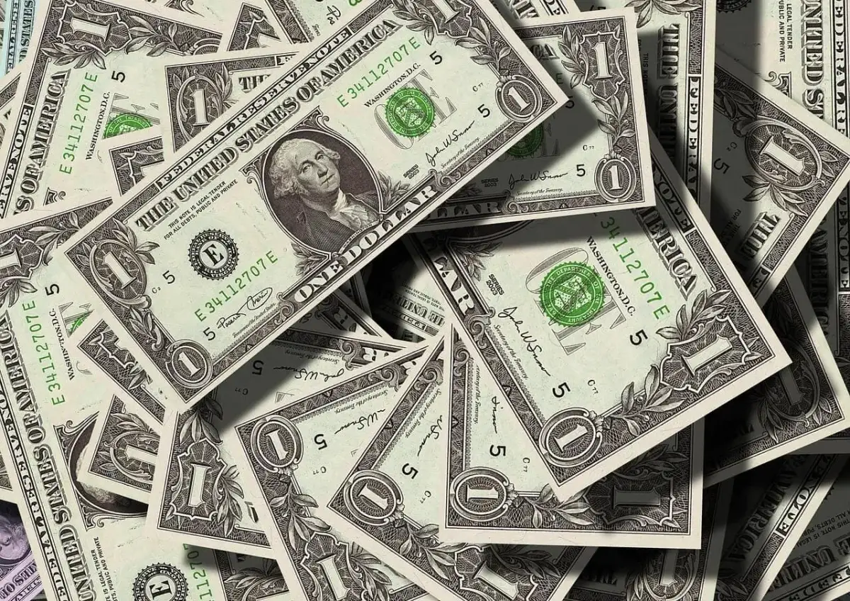 Stosy dolarowych banknotów. Kto ponosi koszty działu spadku u notariusza? Pieniądze mogą pomóc w tej kwestii.