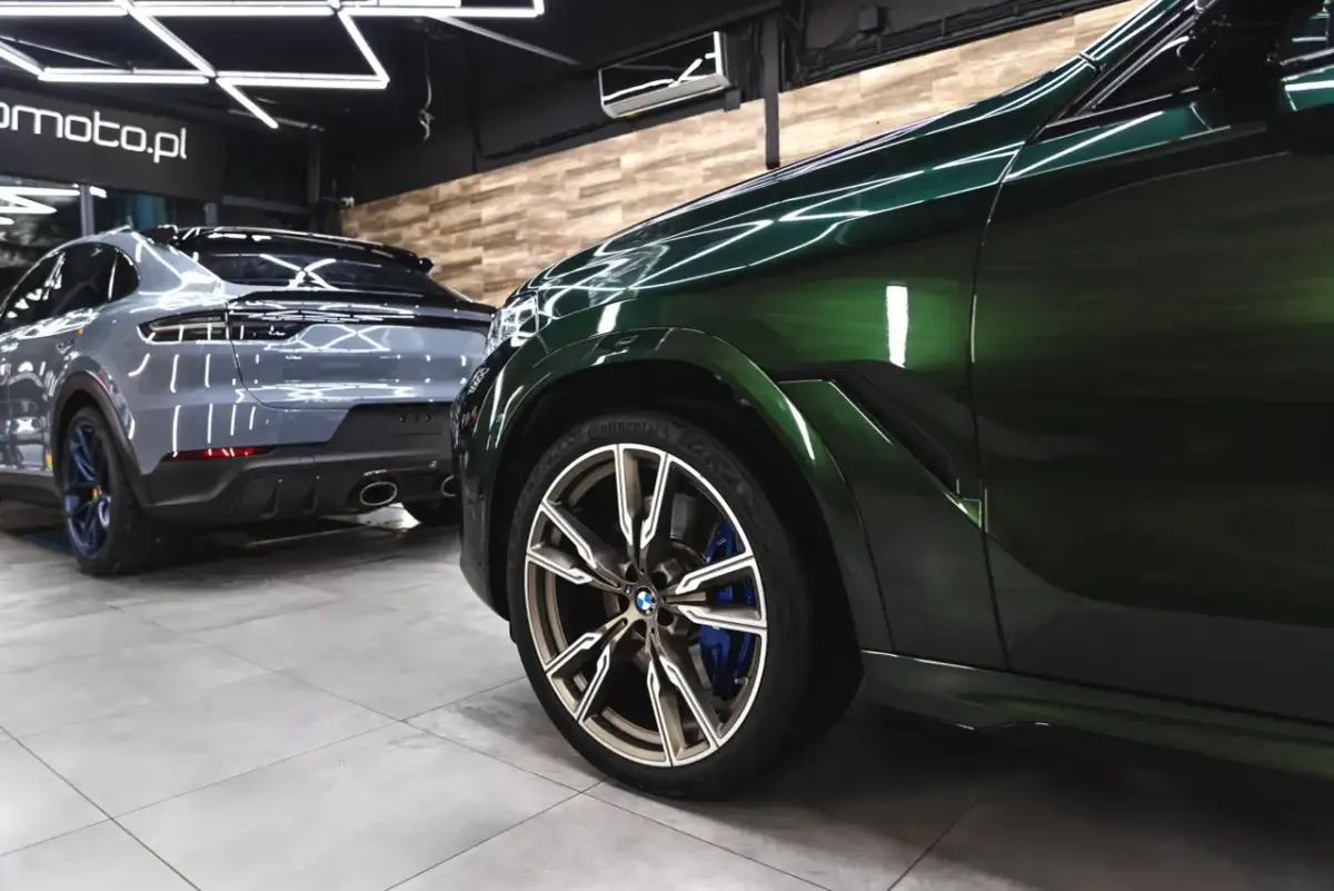 Błyszczące, zielone BMW i szary Porsche w profesjonalnym studiu auto detailing.