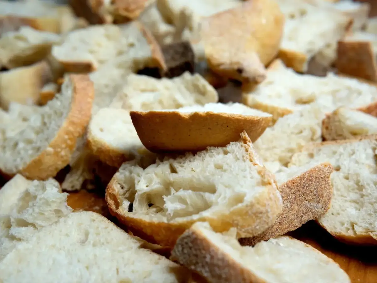 Kawałki czerstwego chleba pokrojone w kostkę i plastry, gotowe do zapiekanki.