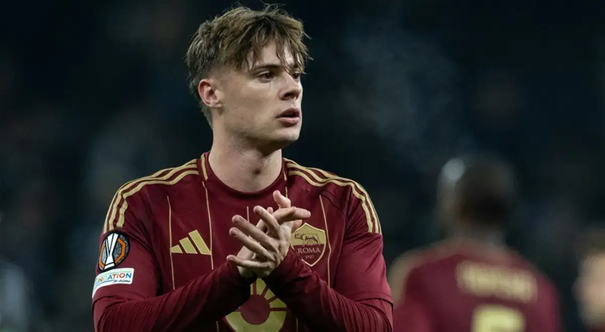 Piłkarz Nicola Zalewski w bordowej koszulce AS Roma z żółtymi pasami na ramionach.
