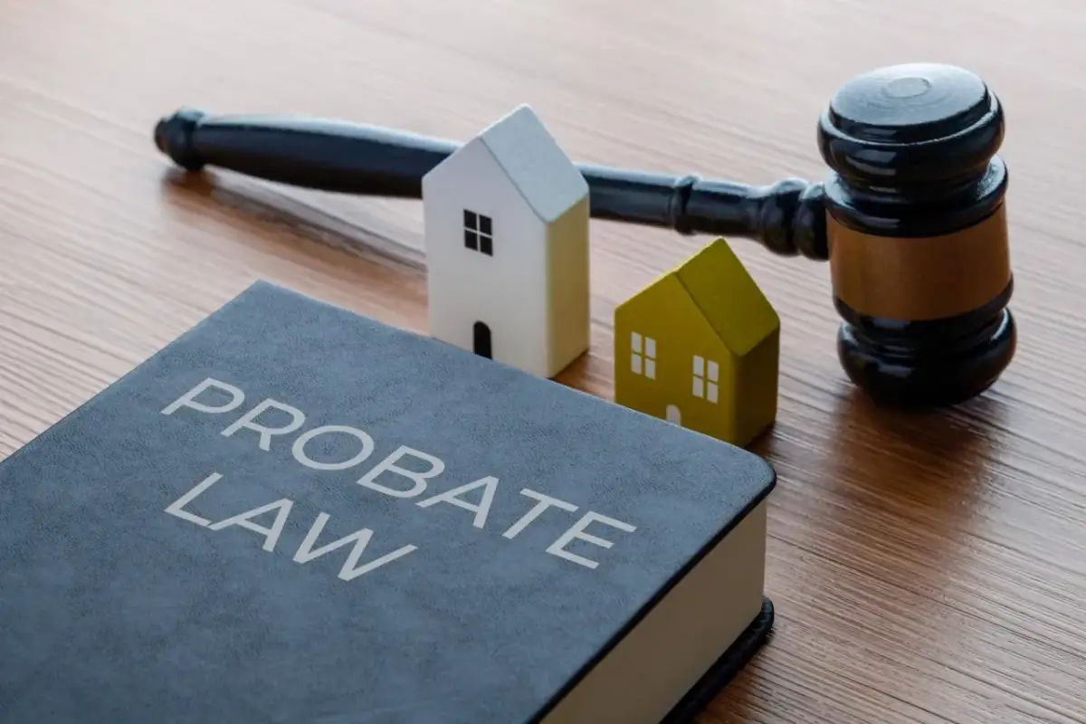 Księga "Probate Law", młotek sędziowski i dwa domki symbolizują dziedziczenie. Dowiedz się, ile procent zachowek przysługuje.