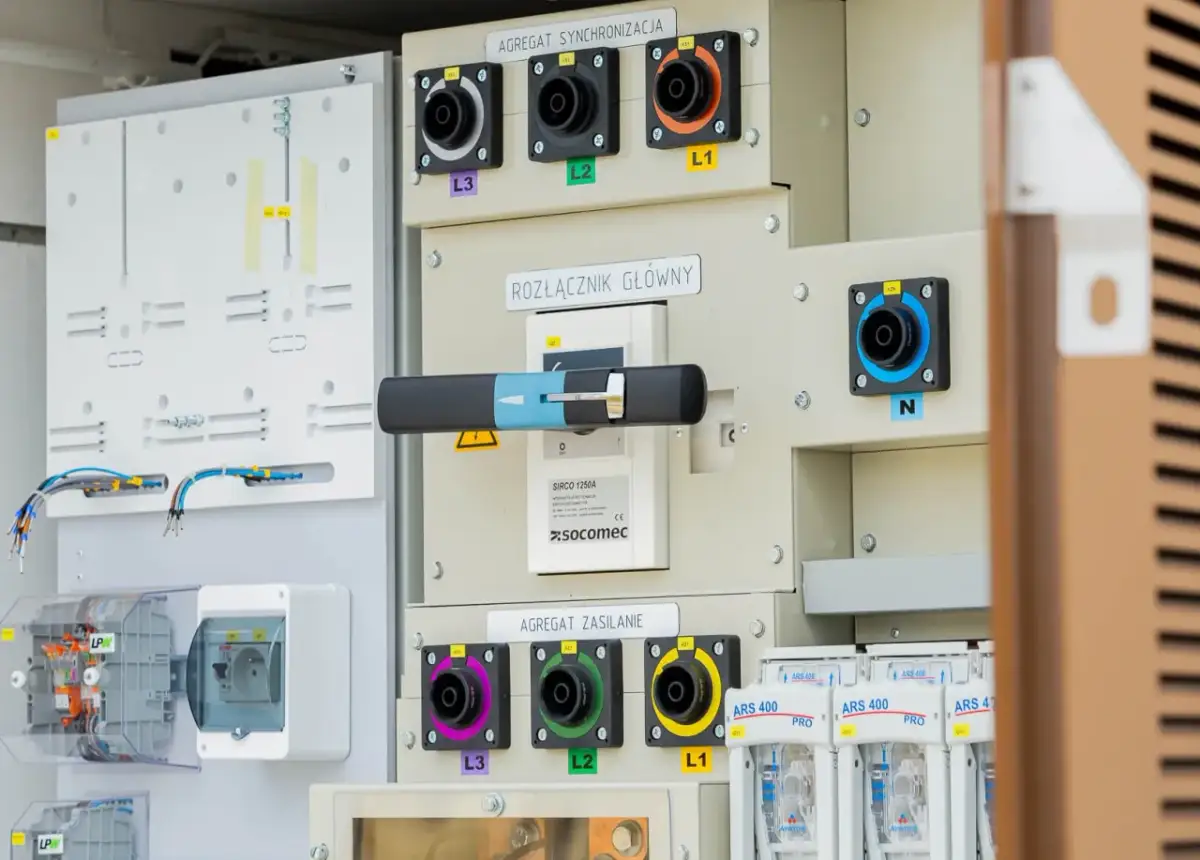 Panel sterowania z rozłącznikiem głównym i agregatami synchronizacji i zasilania. Widoczne złącza L1, L2, L3, N oraz bezpieczniki. System wykorzystuje izolację SF6.