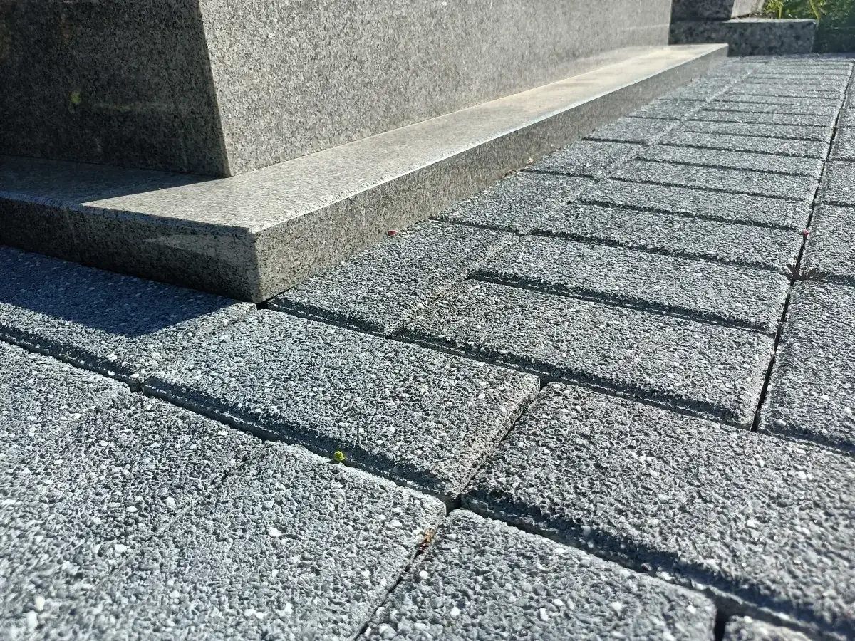 Szare kostki brukowe tworzą ścieżkę wokół pomnika. Idealne, by położyć wokół pomnika, tworząc schludne i trwałe otoczenie.