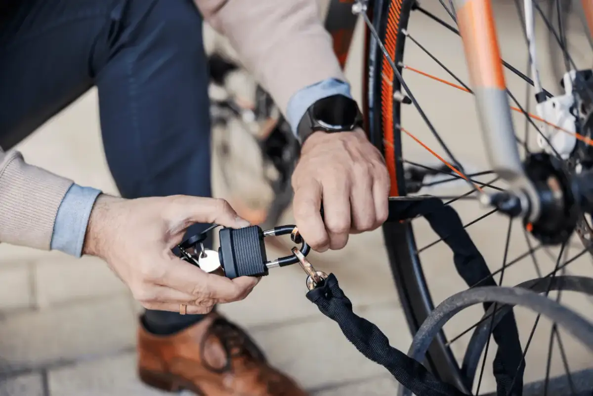 Mężczyzna z kluczykami zamyka rower na kłódkę. To dobry sposób, jak oznakować rower, by był bezpieczny.