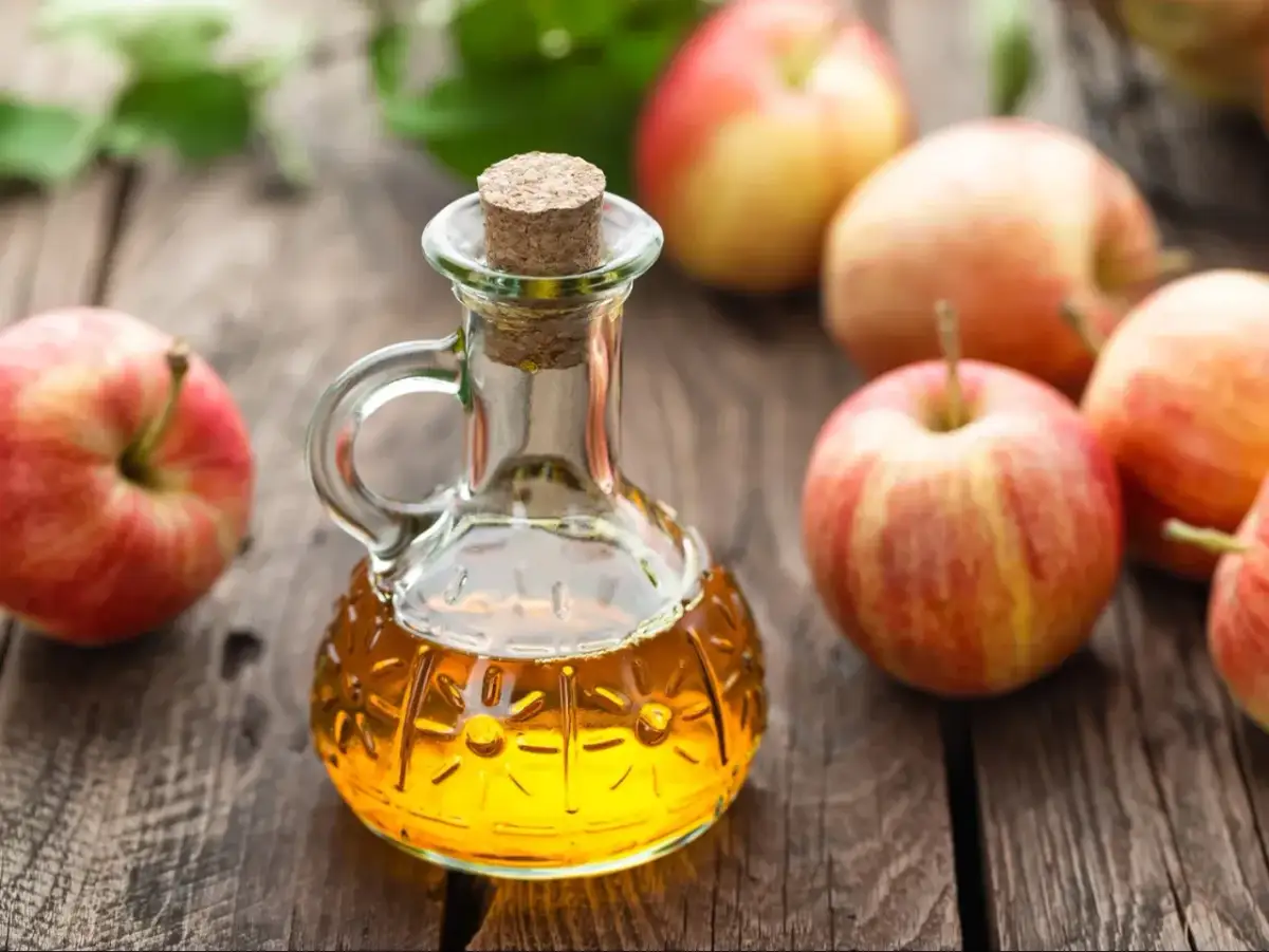 Jabłka i buteleczka z octem jabłkowym. Naturalny sposób, jak odkwasić organizm.