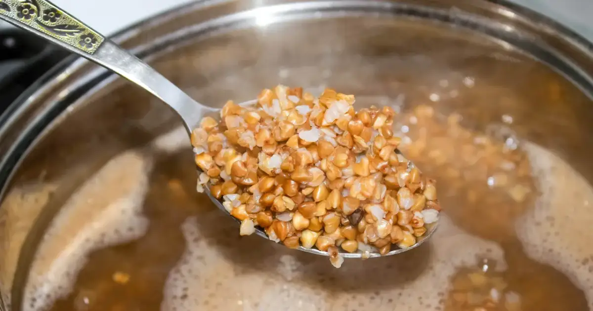 Łyżka gotowanej kaszy gryczanej, idealnej na odchudzanie, unosząca się nad bulgoczącym garnkiem.