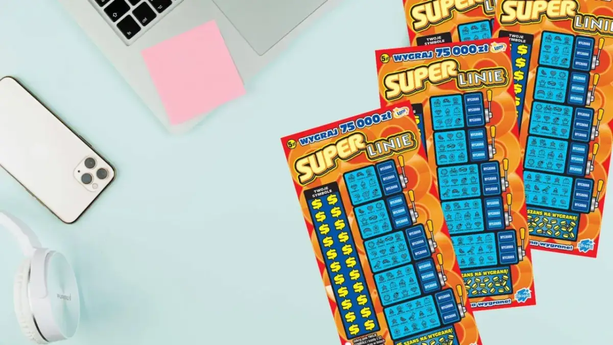 Zdrapki "Super Linie" leżą obok telefonu, słuchawek i notatnika.