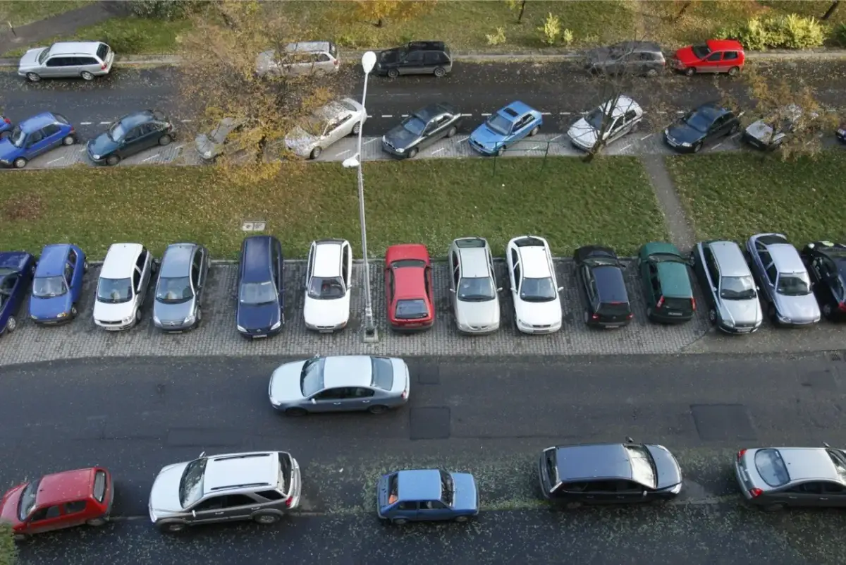 Wiele samochodów zaparkowanych pod blokiem, przypominające o przepisach parkowania.