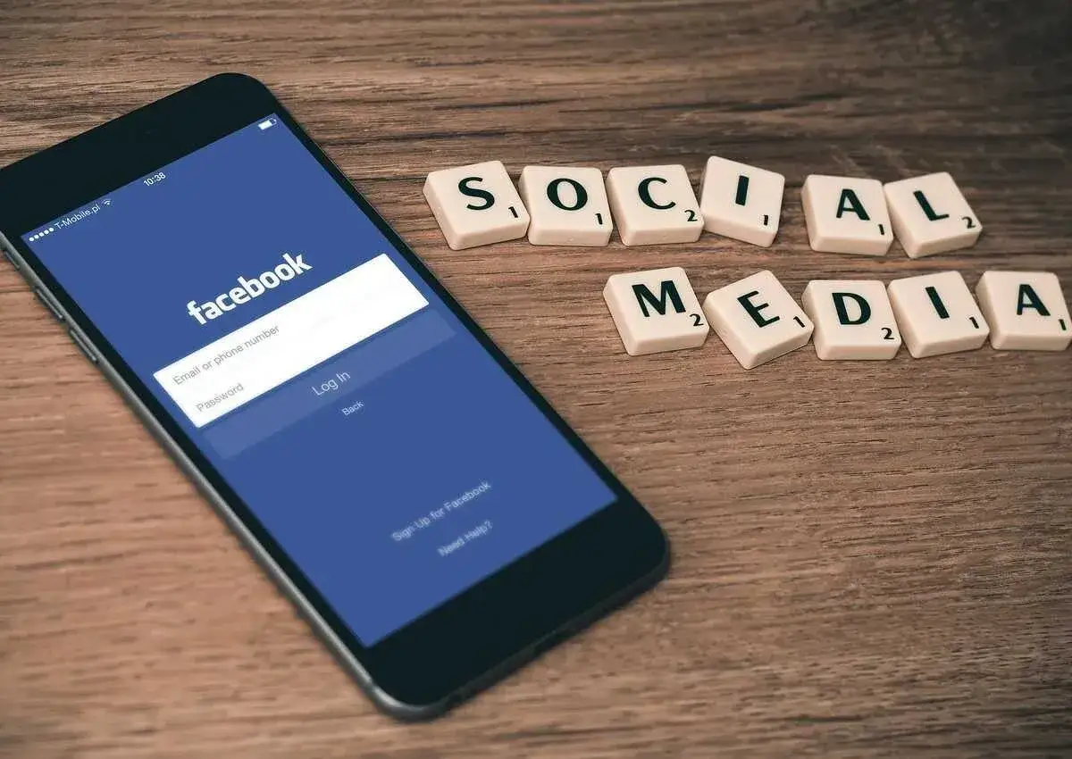 Smartfon z ekranem logowania Facebooka i kafelki z napisem "SOCIAL MEDIA".