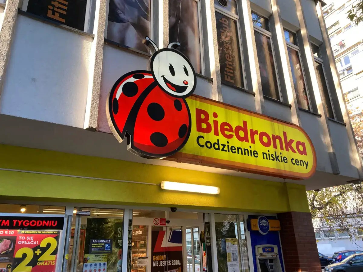 Logo Biedronki i szyld sklepu. Zastanawiasz się, jak odebrać wygraną ze zdrapki Biedronka? Sprawdź w sklepie!