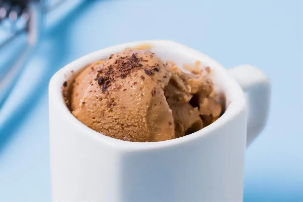 Brązowe lody dla psa w białej filiżance, posypane wiórkami. Gdzie kupić takie smakołyki?