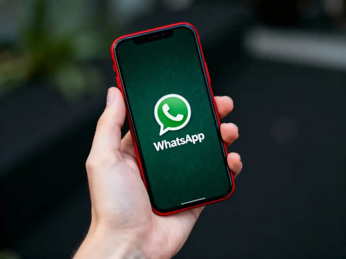 Dłoń trzyma iPhone'a z logo WhatsApp. Dowiedz się, jak przenieść czaty WhatsApp z Androida na iPhone.