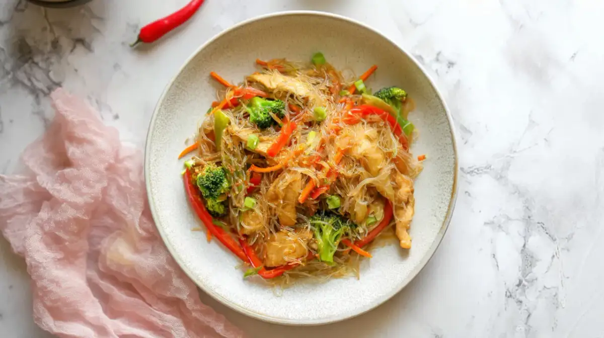 Pyszny makaron sojowy z kurczakiem i warzywami, jak od chińczyka. Danie wygląda apetycznie i kolorowo.