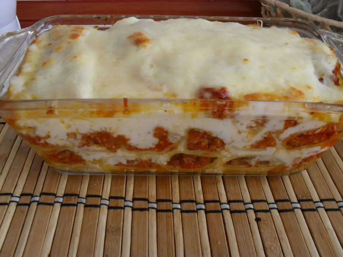 Pyszne cannelloni z mięsem mielonym, zapieczone pod warstwą sera i sosu, prezentują się apetycznie w szklanym naczyniu.