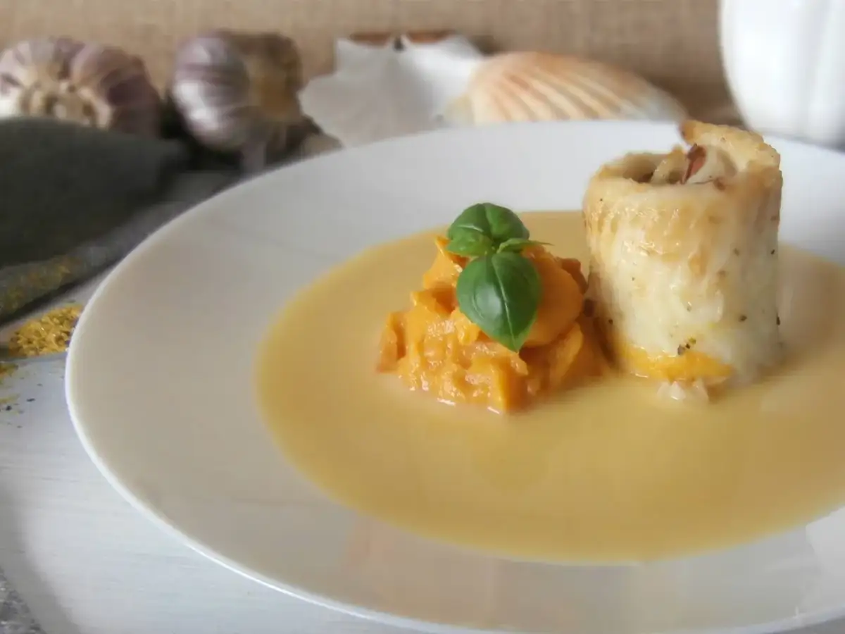 Roladka rybna z puree z dyni, udekorowana bazylią, podana w kremowym sosie beurre blanc.