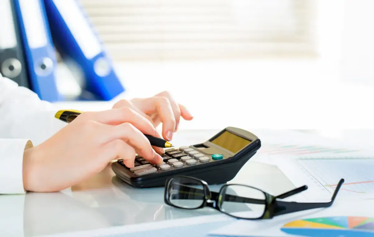 Dłonie na kalkulatorze, obok okulary i wykresy. Czy Vivus rozkłada na raty? Analiza finansowa.