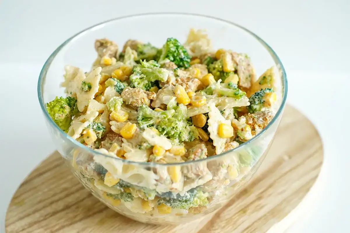 Pyszna sałatka z brokułem i kurczakiem, pełna kolorów i smaku, w szklanej misie na drewnianej desce.