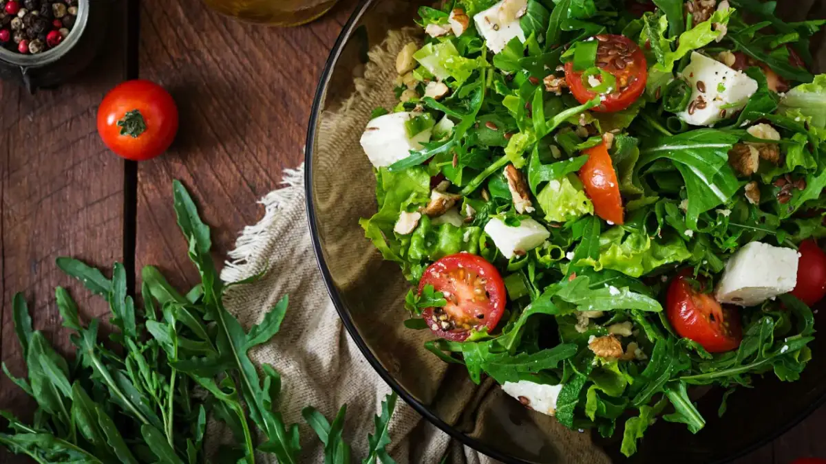 Pyszna sałatka na grilla z rukolą, pomidorkami, serem feta i orzechami. Idealna na letnie przyjęcie.
