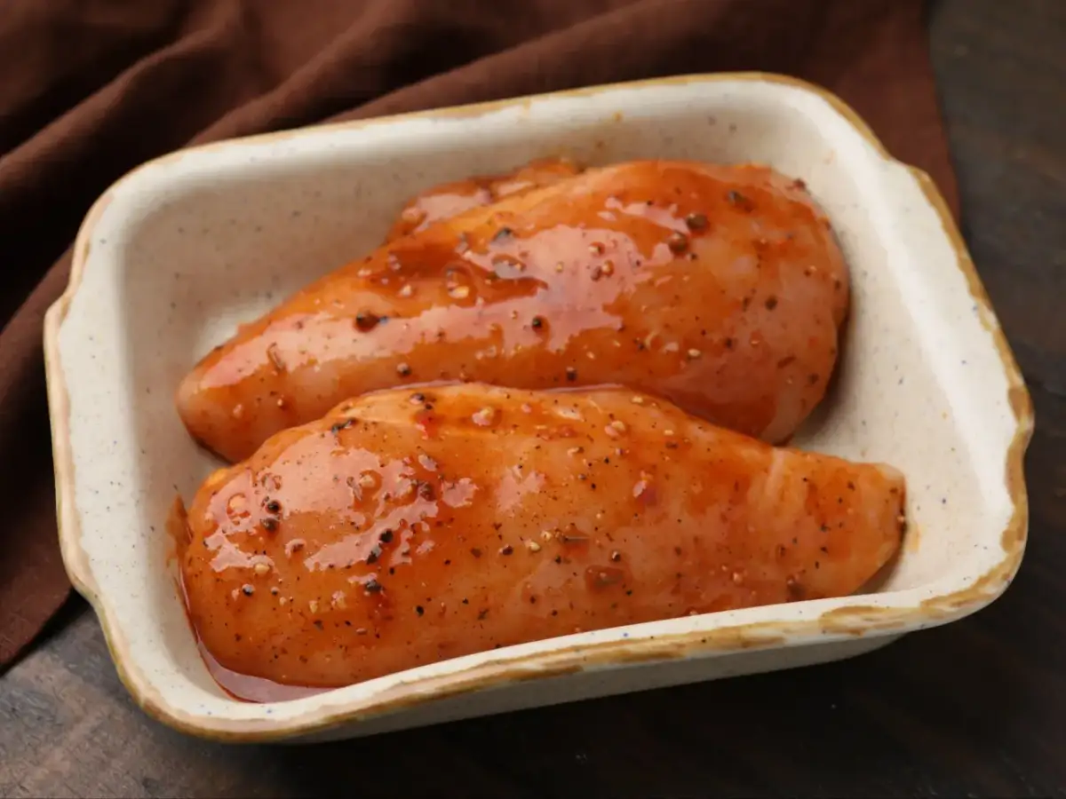 Dwie soczyste piersi z kurczaka w marynacie z przyprawami, gotowe do pieczenia.