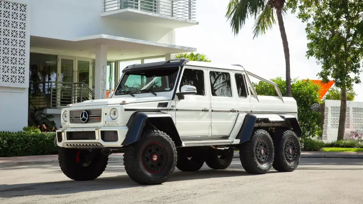 Potężny biały Mercedes G-Class 6x6 z masywnymi oponami i sześcioma kołami, gotowy na każdą przygodę.