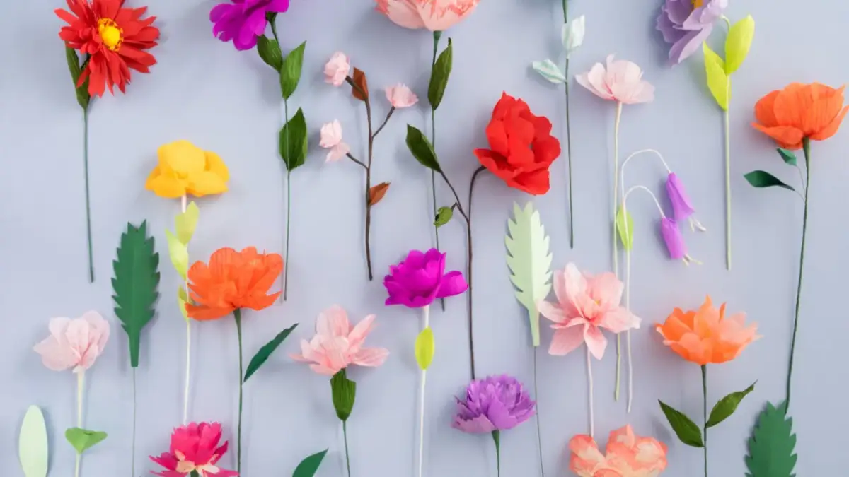 Kolorowe kwiaty z bibuły, różne wzory i kształty, tworzą bujny, papierowy ogród.