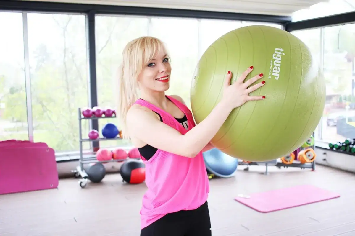 Uśmiechnięta blondynka z piłką gimnastyczną. Czy brzuch można ćwiczyć codziennie? Ona wie!