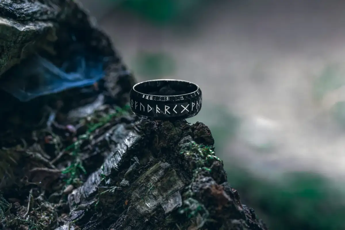 Czarna obrączka z runami na pniu drzewa.