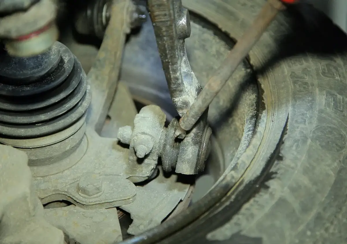 Mechanik bada przyczynę chrobotania przy skręcaniu kierownicą, sprawdzając zużyte elementy zawieszenia i przegub.