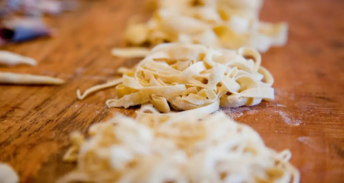 Świeży makaron na drewnianym blacie. Czy pies może jeść ryż i makaron? To pytanie nurtuje wielu właścicieli czworonogów.