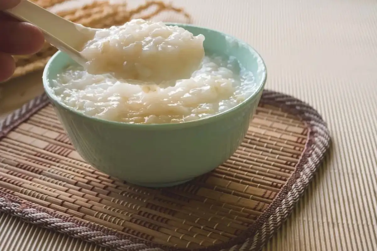Łyżka z kleikiem ryżowym nad miseczką. Prosty kleik ryżowy przepis na pyszne i sycące danie.