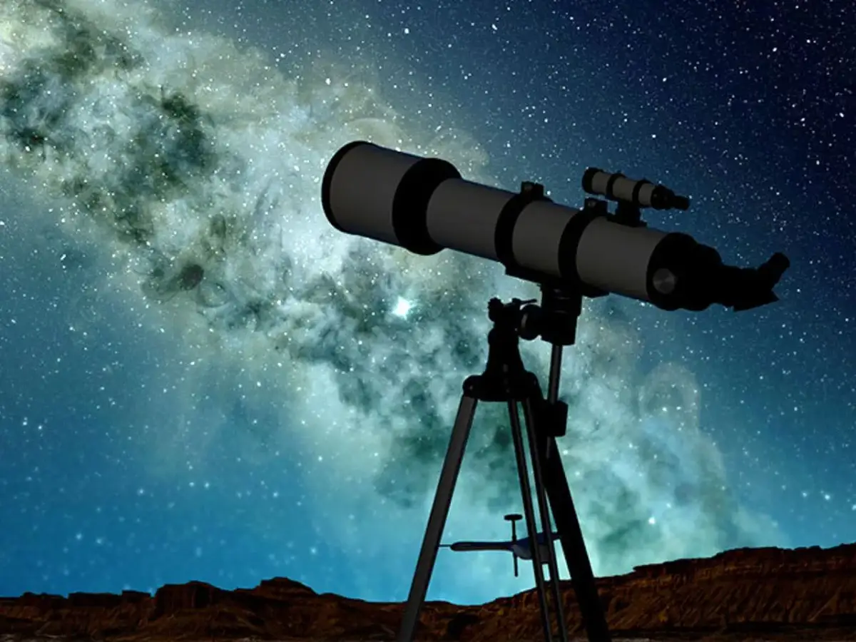 Teleskop na statywie na tle Drogi Mlecznej i nocnego nieba.