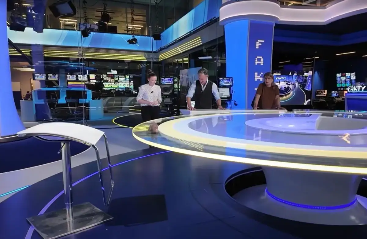 Trzy osoby stoją przy okrągłym stole w nowoczesnym tvn studio sękocin. W tle monitory i sprzęt.