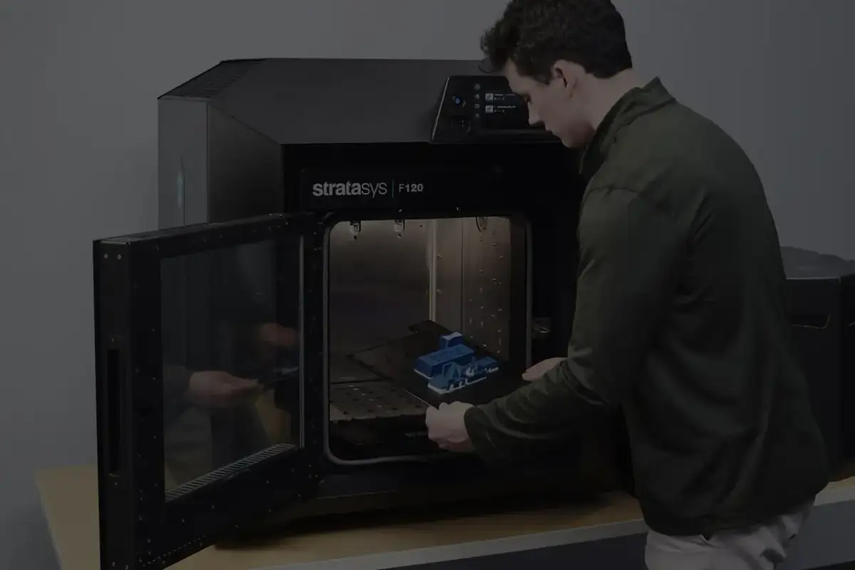 Mężczyzna wkłada wydrukowany model do drukarki 3D Stratasys F120.