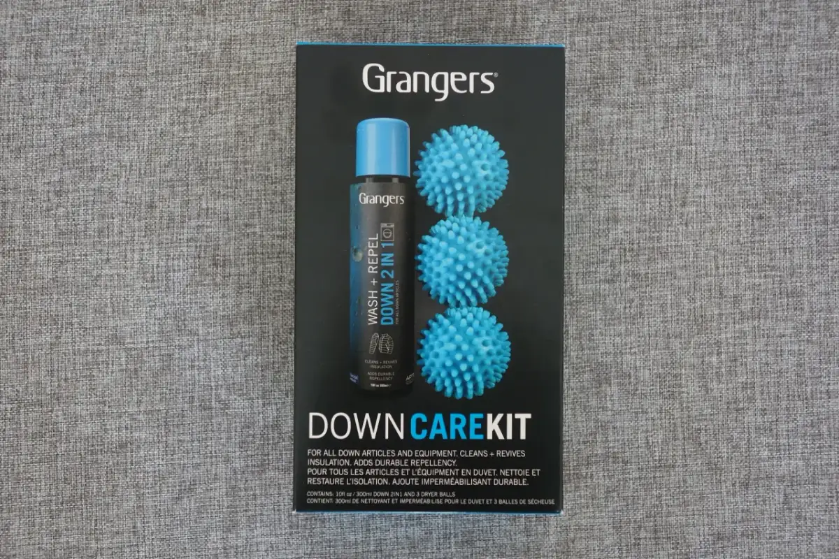 Zestaw Grangers Down Care Kit zawiera płyn do prania kurtek puchowych i 3 niebieskie piłeczki do suszarki, które pomagają odzyskać objętość.