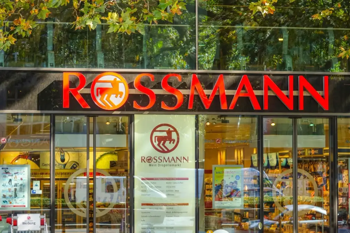 Logo i szyld drogerii Rossmann z czerwonym napisem i pomarańczowym symbolem konia.