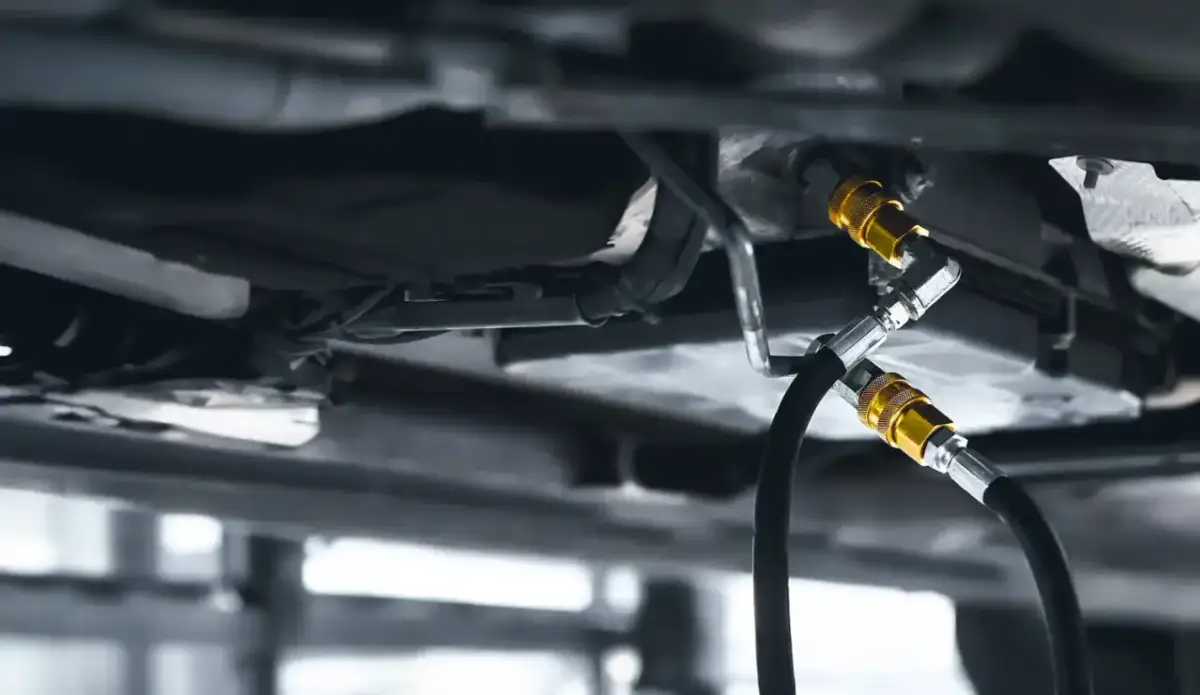 Podwozie samochodu z podłączonymi wężami do dynamicznej wymiany oleju.