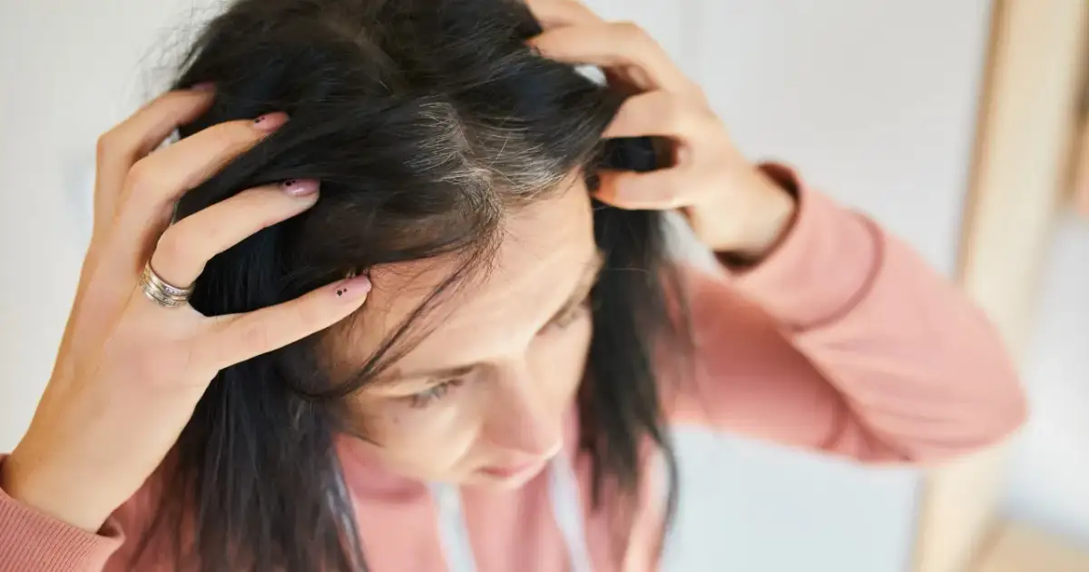 Kobieta sprawdza siwe włosy. Może warto rozważyć suplementację cynku dla zdrowia włosów.