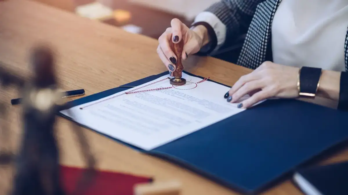 Kobieta pieczętuje umowę przedwstępną sprzedaży domu. Dokument jest przypieczętowany pieczęcią.