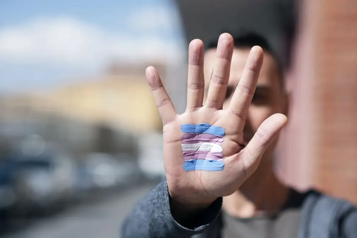 Dłoń z namalowaną flagą osób transpłciowych. Kto to jest transseksualista? To osoba, której tożsamość płciowa różni się od płci przypisanej przy urodzeniu.