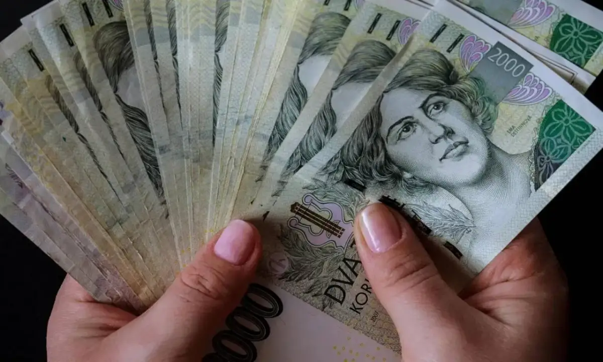 Dłonie trzymające stos banknotów 2000 koron czeskich. Czy to znak, które banki są zagrożone upadłością w Polsce?